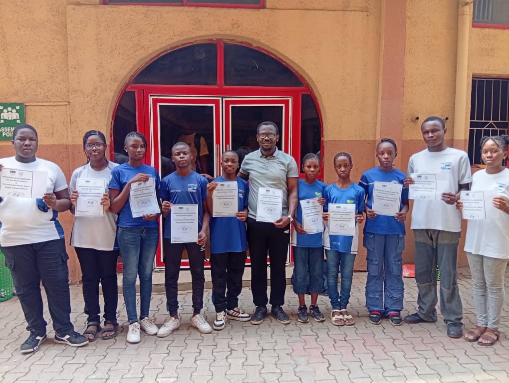 Students from The Ambassadors Schools in Nigeria stood holding certificates of collaboration for Pledge Towards Kindness